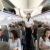 A flight attendant is directing passengers on an airplane.