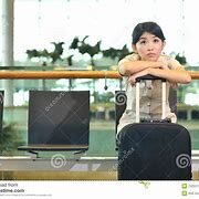 A girl sitting on top of luggage in an airport.