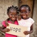 Two young girls holding a sign that says hope.